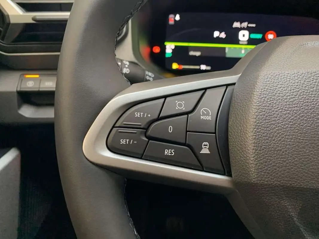 Gros plan sur les commandes au volant cuir du DACIA BIGSTER Hybrid 155, avec tableau de bord digital en arrière-plan.