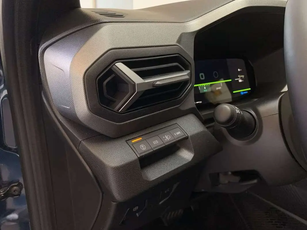 Détail de la console gauche avec aérateur hexagonal et commandes sur fond noir du Dacia Bigster Hybrid 155 bleu indigo.