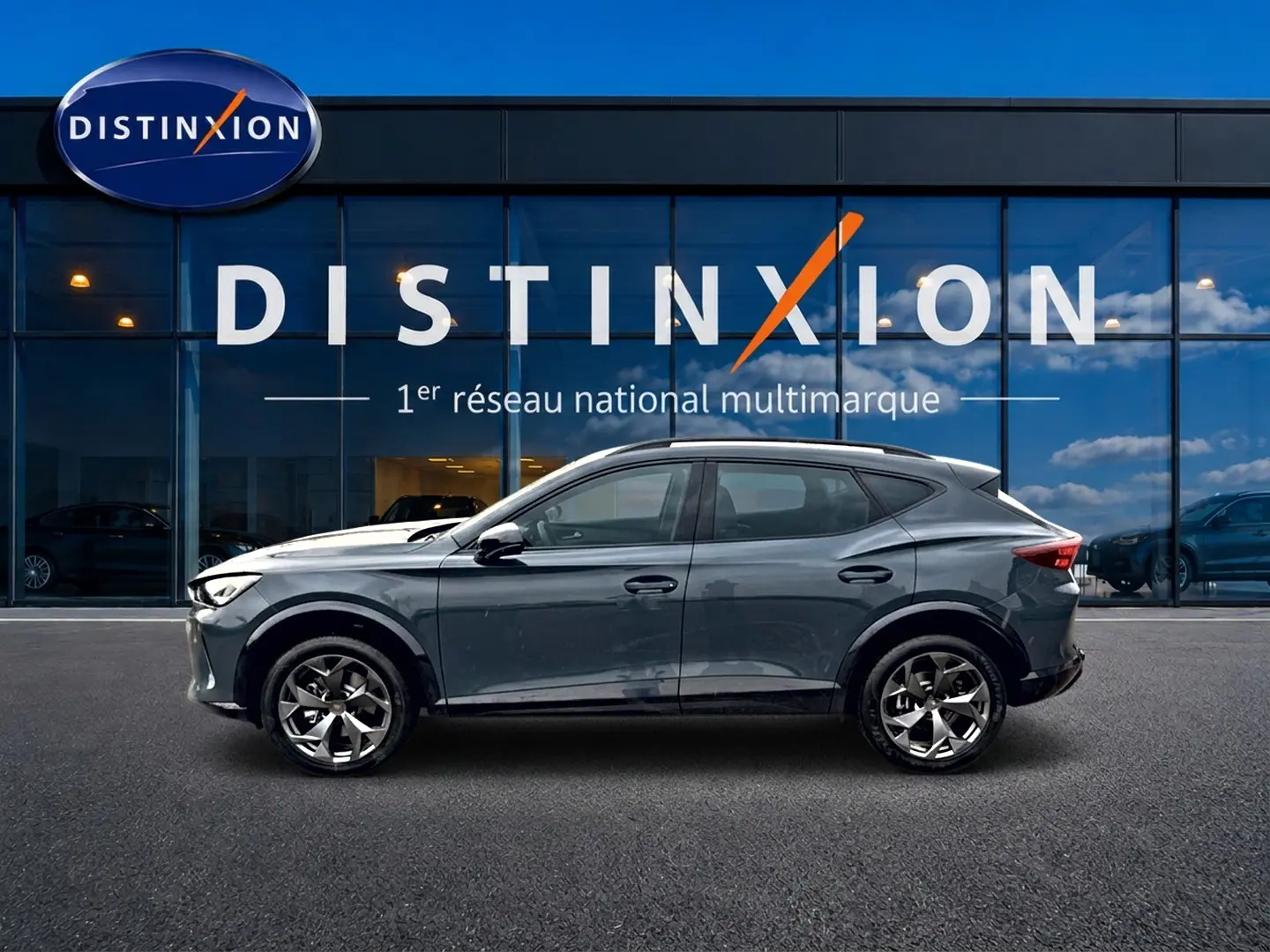 Vue latérale droite d'un CUPRA Formentor bleu fjord 2026 garé devant une vitrine avec logo Distinxion.