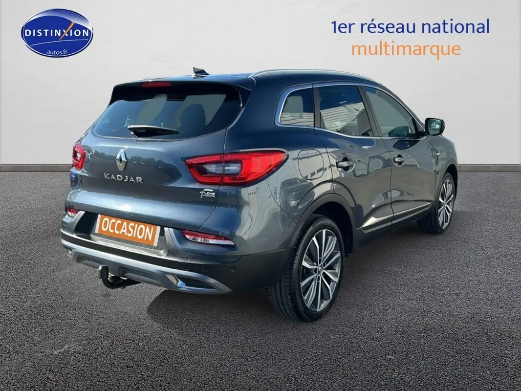 Vue 3/4 arrière droite d'un Renault Kadjar gris foncé avec jantes alliage 19 pouces et barres de toit.