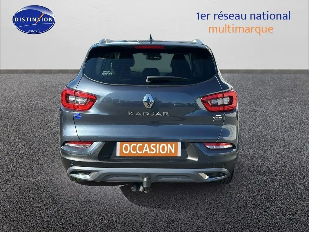 Vue arrière d'un Renault Kadjar gris foncé avec barres de toit et attelage visible sur un parking.