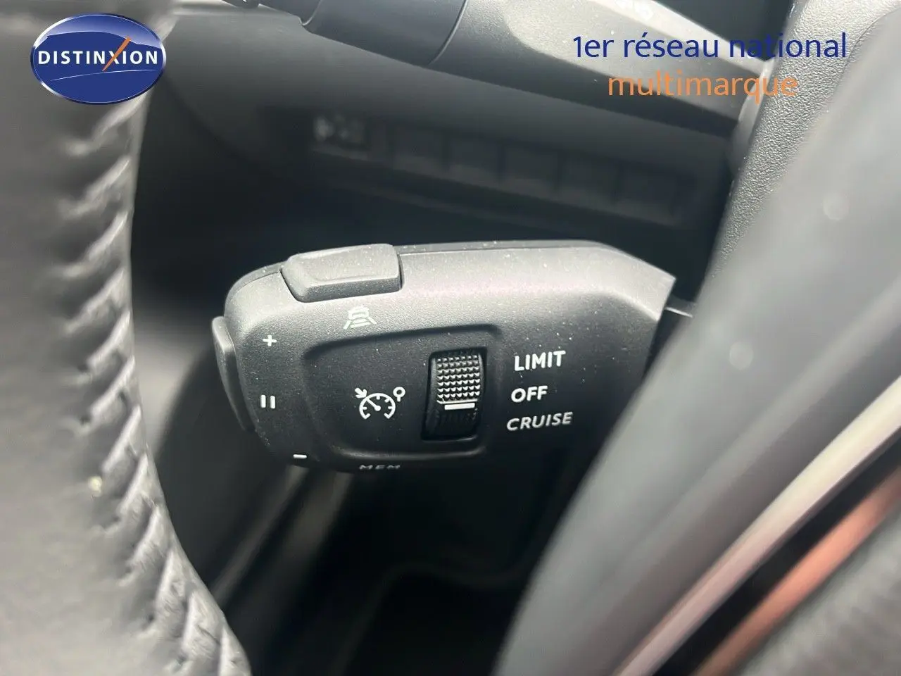 Gros plan sur la commande de régulateur de vitesse à gauche du volant d'une Peugeot 2008 blanc Okenite métal 2025.