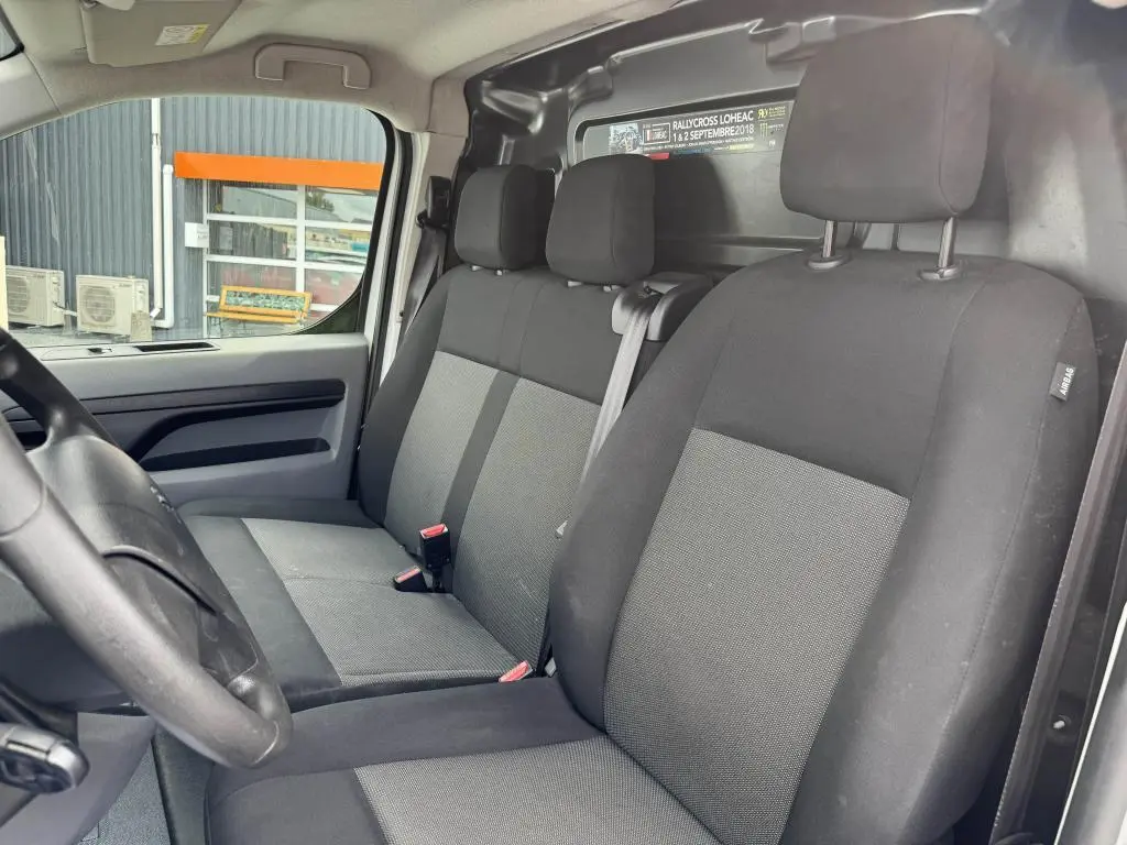 Vue intérieure côté conducteur du Peugeot Expert Fourgon 2018 avec sièges tissu tri-ton noir et gris et cloison tôlée arrière.
