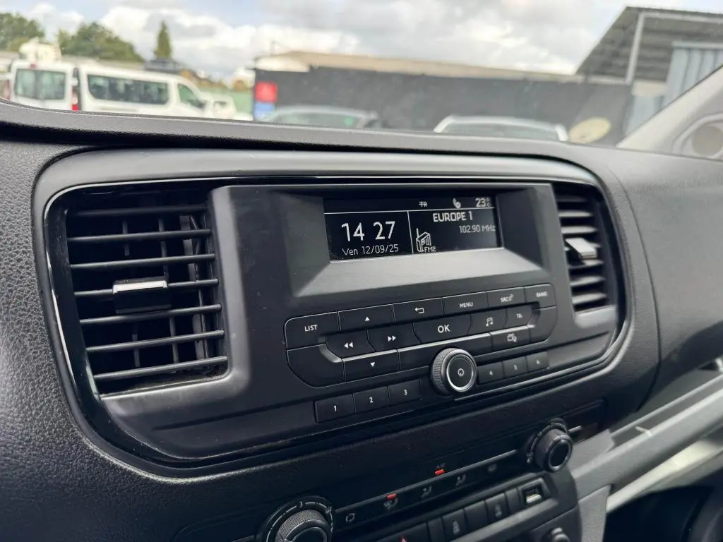 Vue rapprochée du tableau de bord noir du Peugeot Expert Fourgon blanc, mettant en valeur l'écran radio et les commandes centrales.