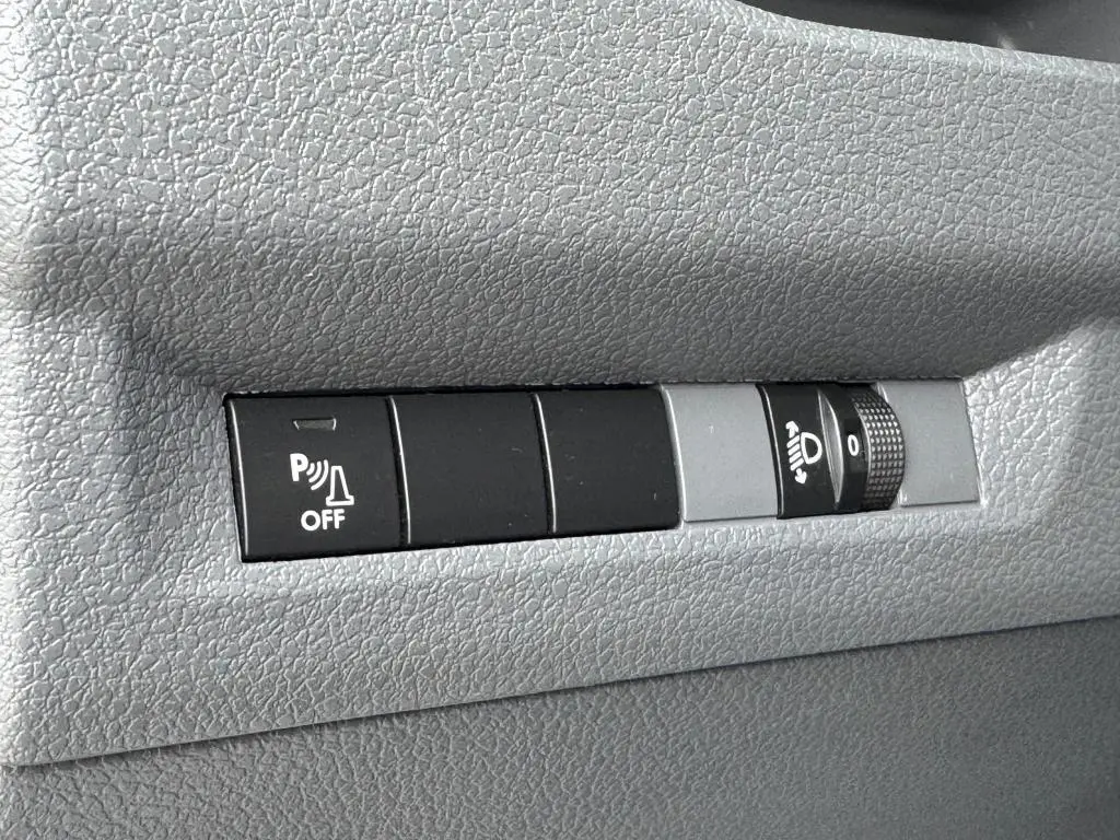 Gros plan sur les commandes de réglage des feux et désactivation du radar de stationnement du Peugeot Expert Fourgon blanc.