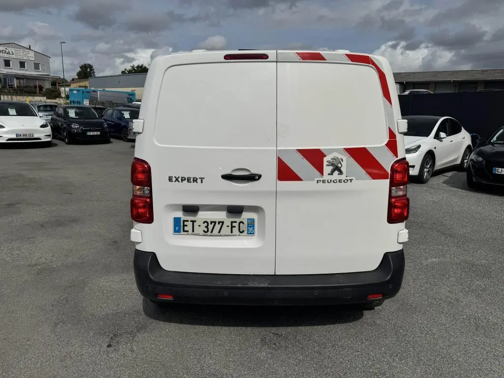 Vue arrière du Peugeot Expert Fourgon blanc avec bandes réfléchissantes rouges et blanches sur la porte droite.