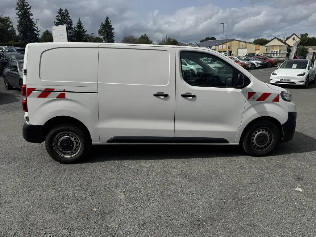 Peugeot Expert Fourgon blanc vue de profil côté gauche avec bandes rouges réfléchissantes sur ailes avant et arrière.