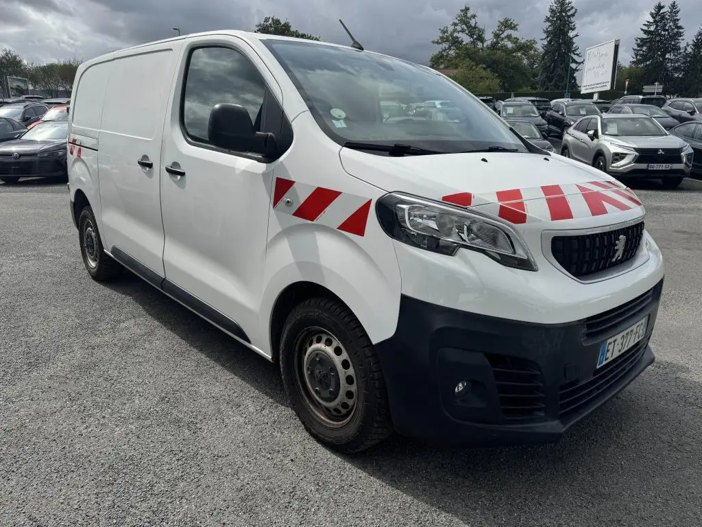 Vue 3/4 avant droit d’un Peugeot Expert Fourgon blanc avec bandes rouges diagonales sur capot et ailes, boucliers noirs.