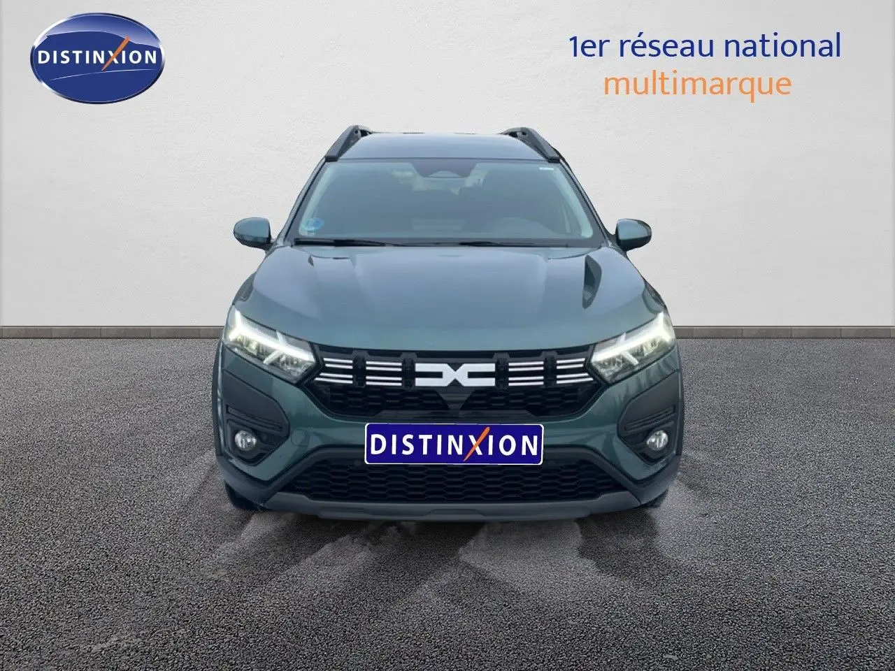 Vue de profil côté gauche d’un Dacia Jogger 2025 vert cèdre métallisé avec jantes noires et toit noir en intérieur showroom.