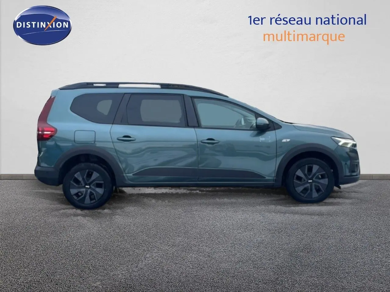 Vue intérieure côté conducteur du Dacia Jogger vert cèdre, montrant les sièges noirs et le tableau de bord avec volant et boîte manuelle.