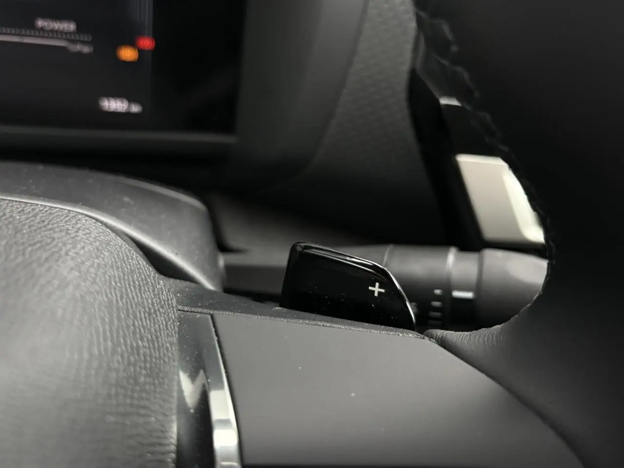 Gros plan sur la palette de changement de rapport droite au volant cuir noir de la Citroën C4 Hybrid 2025.