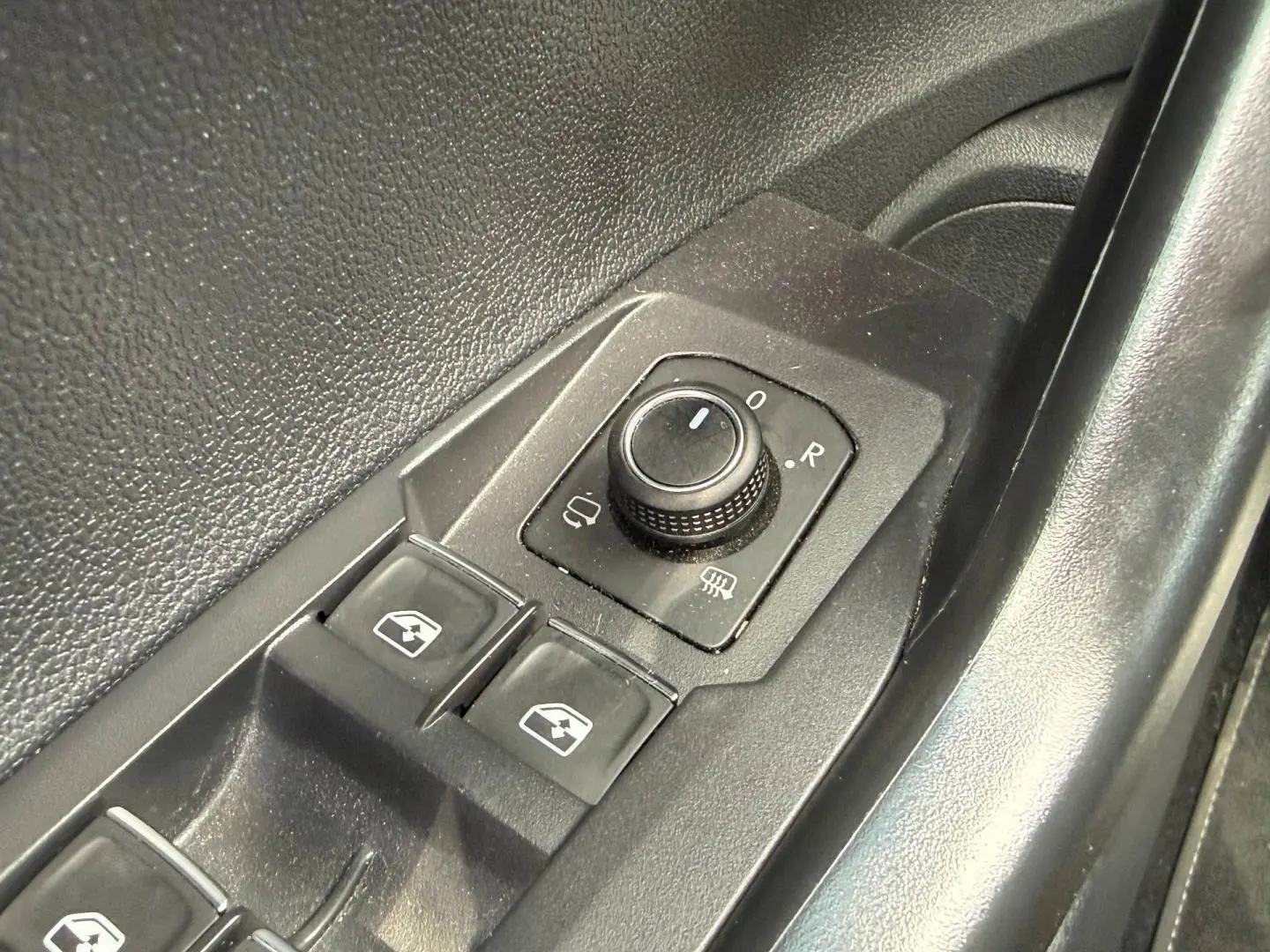 Gros plan sur les commandes de réglage des rétroviseurs et des vitres côté conducteur du Volkswagen Taigo gris 2025.