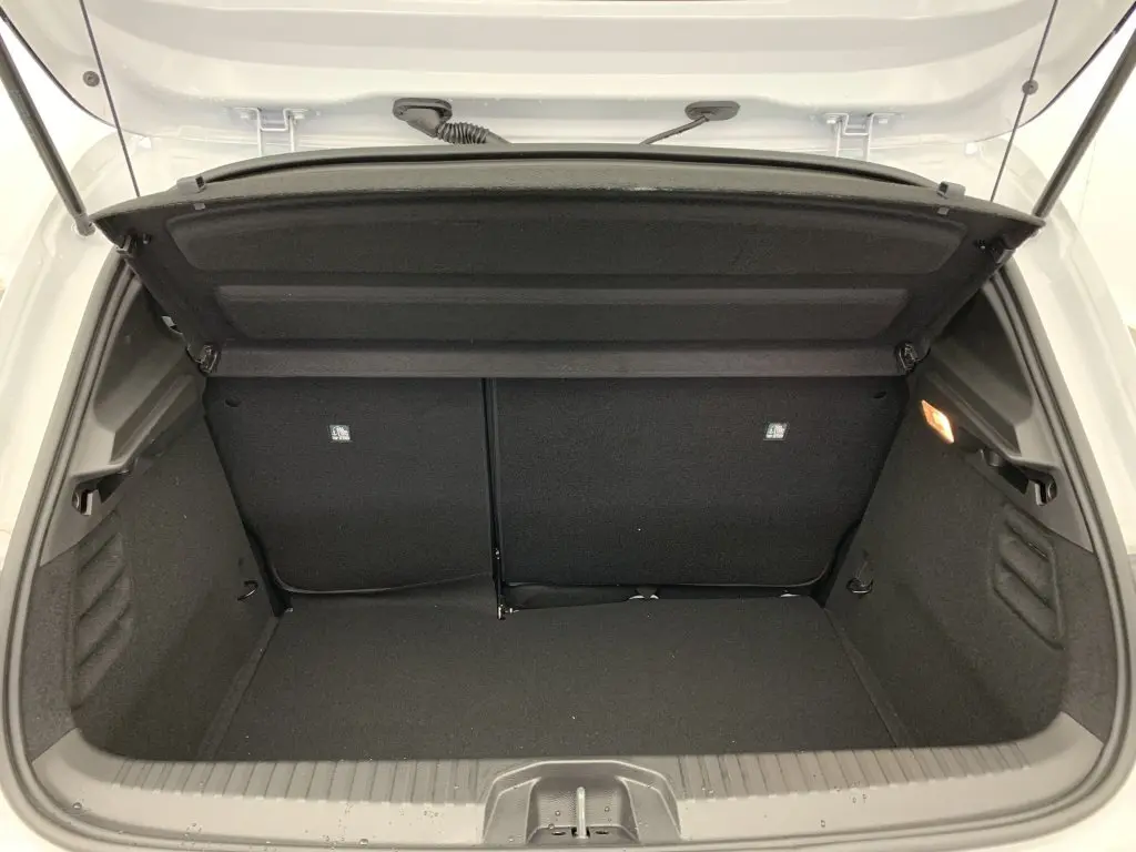 Coffre ouvert vu de l'arrière d'une Renault Clio V blanc glacier, montrant un espace de chargement propre et bien agencé.