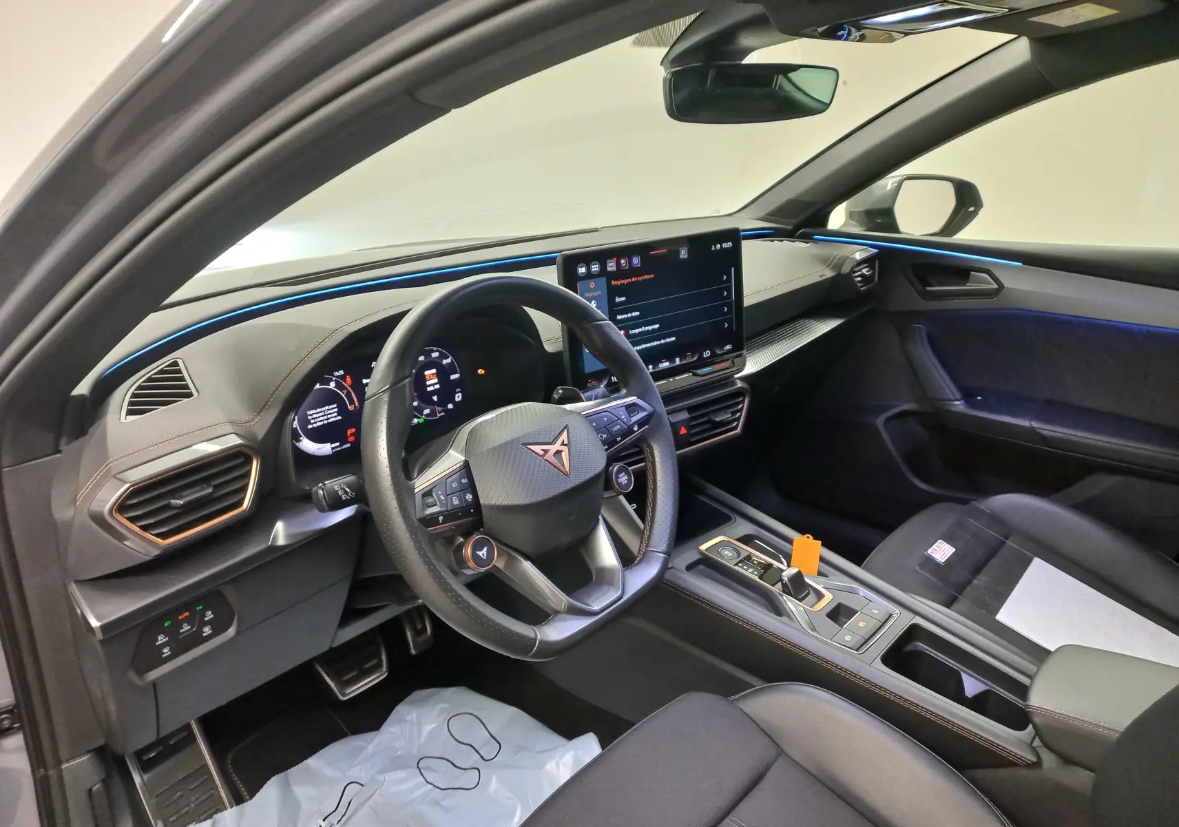 Vue intérieure côté conducteur de la CUPRA Leon Phase 2 avec éclairage d'ambiance bleu et tableau de bord numérique.