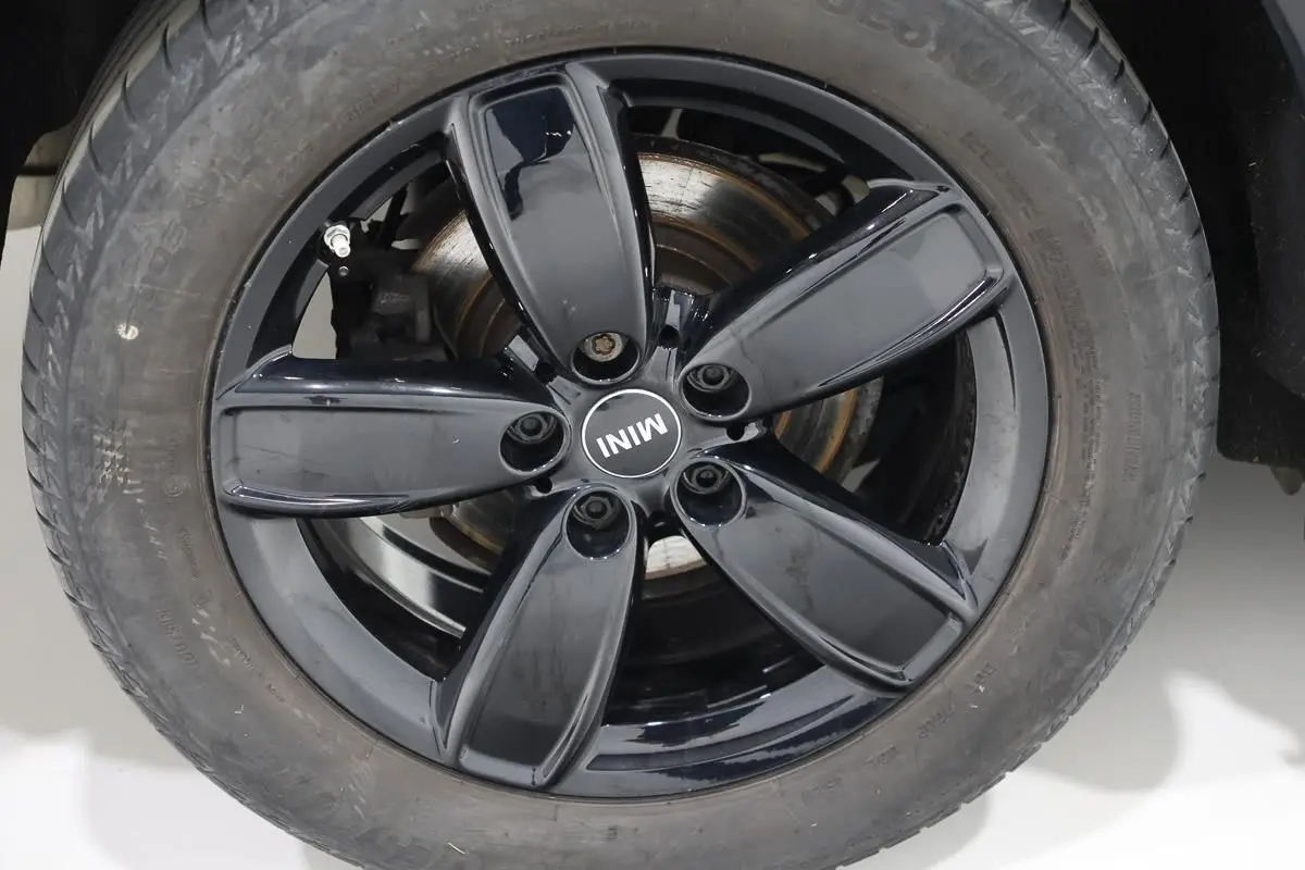 Gros plan sur la roue avant droite d'une MINI Countryman 2021, jante noire brillante avec logo MINI au centre.