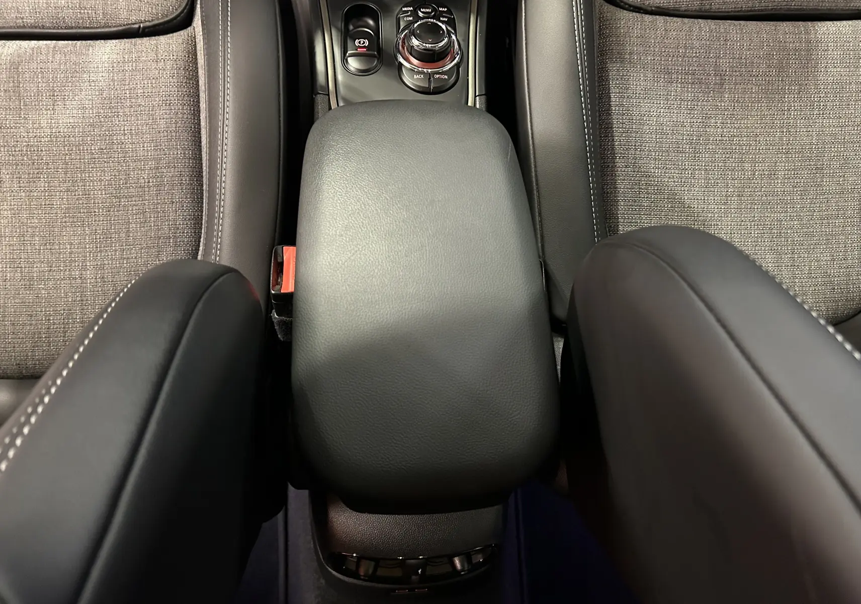 Vue intérieure centrée sur l'accoudoir noir en cuir et la console centrale entre les sièges tissu gris du MINI Countryman.