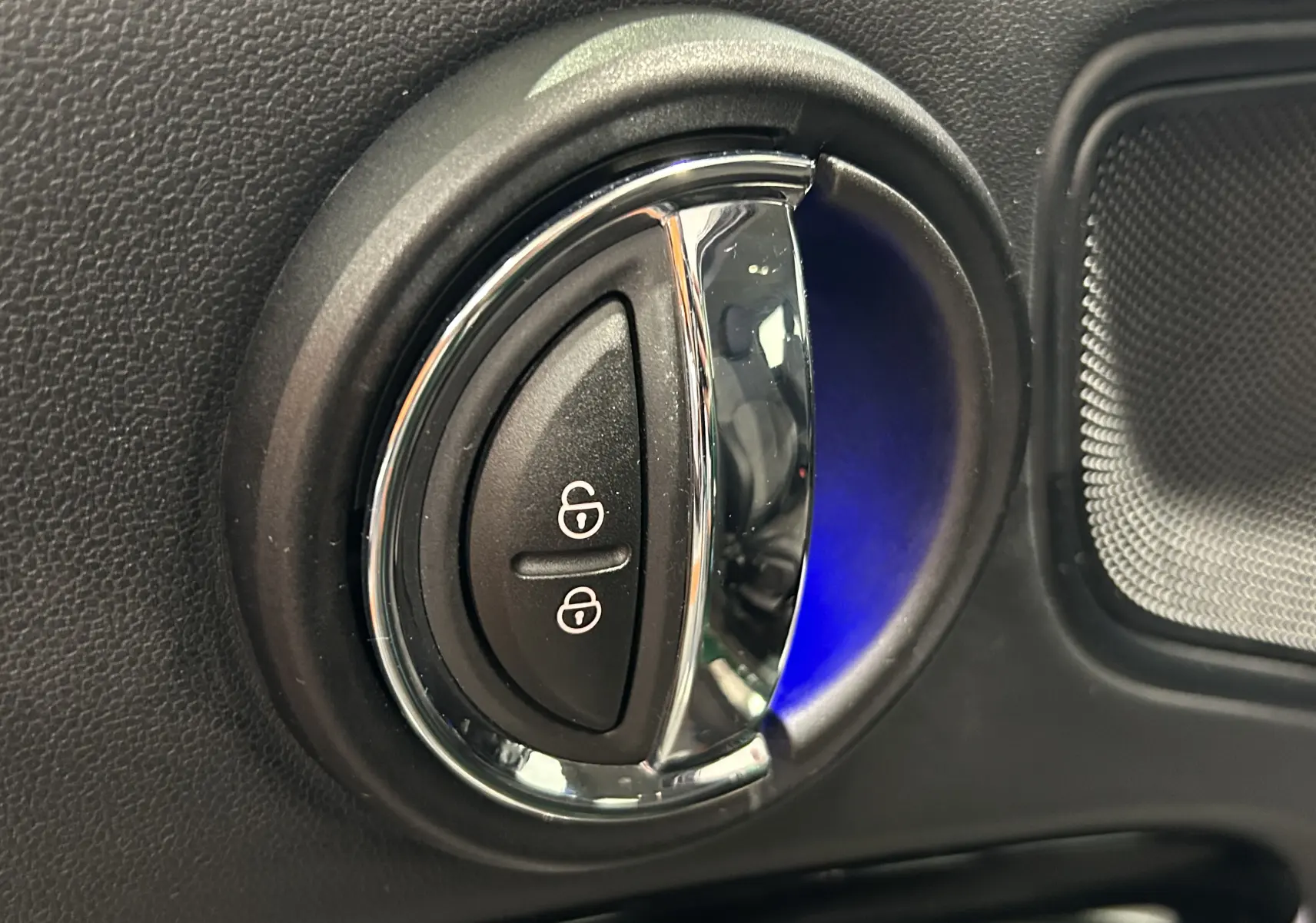 Gros plan sur la commande de verrouillage des portes avec éclairage bleu intérieur d'une MINI Countryman vert métallisé.