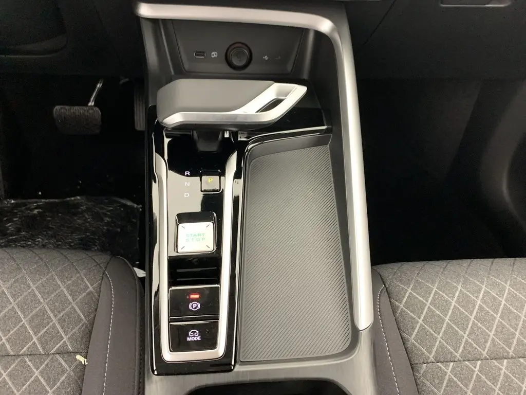 Vue plongeante sur la console centrale noire brillante du MG ZS blanc, avec levier de vitesse automatique et boutons start/stop.