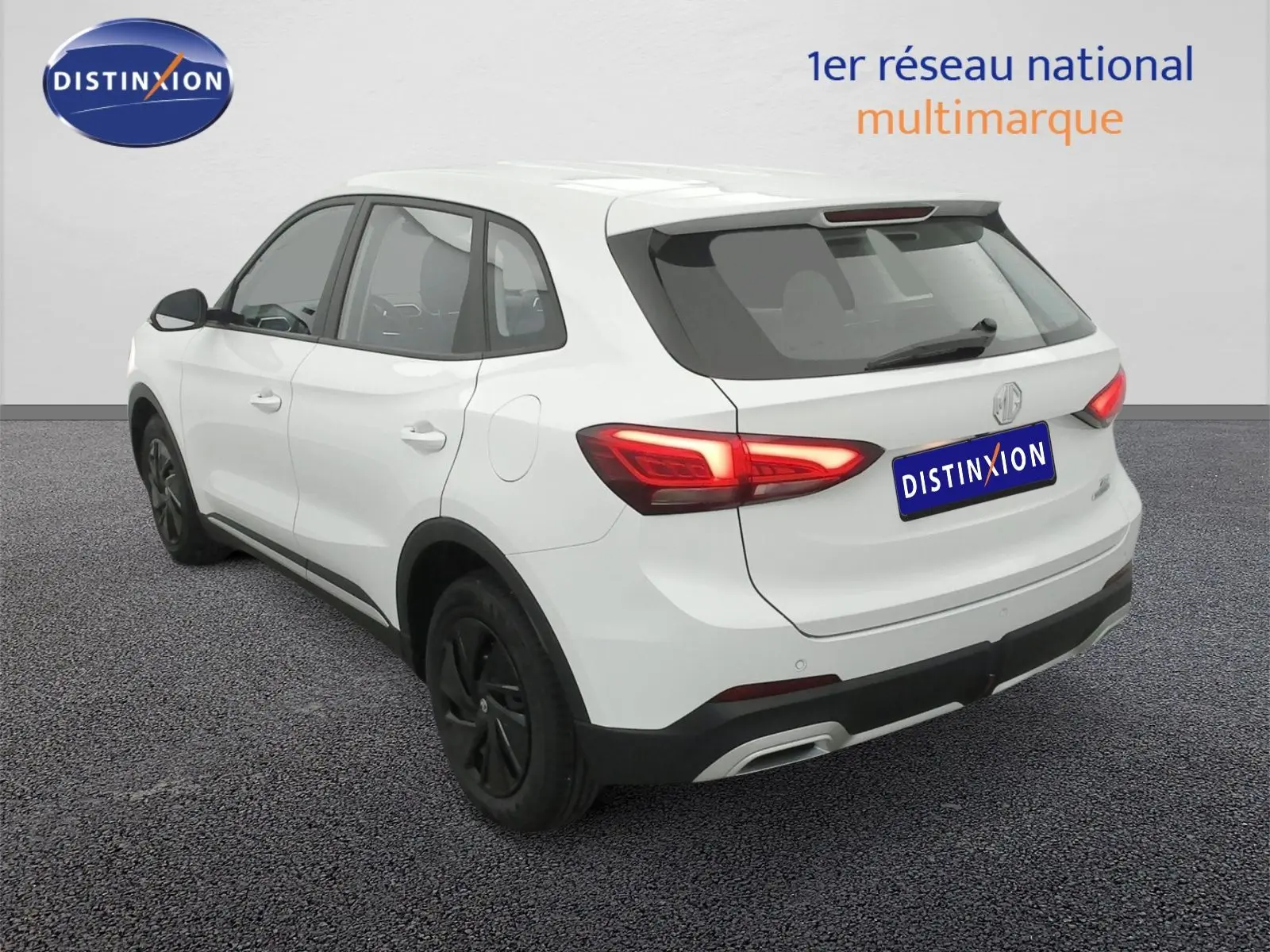 Vue 3/4 arrière droite du SUV MG ZS blanc Dover White avec feux arrière allumés et jantes noires.
