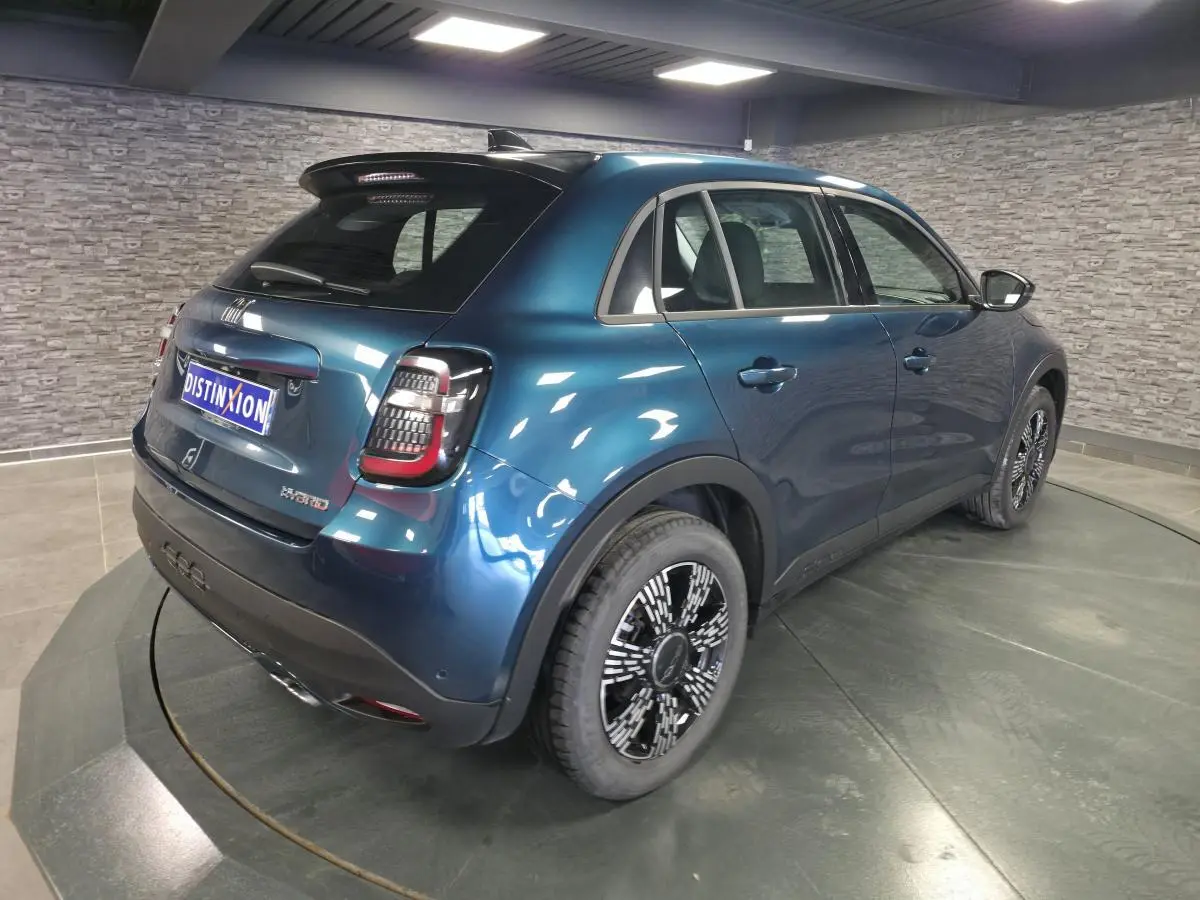 Vue 3/4 arrière droite d'une FIAT 600 hybride bleu métallisé avec jantes alliage et feux arrière LED dans un showroom.