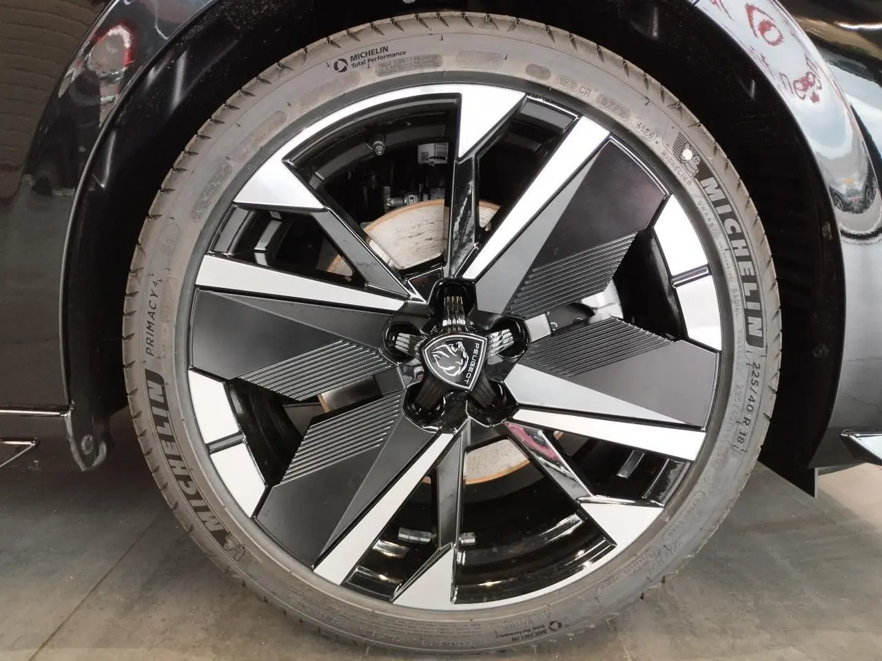 Gros plan sur la jante alliage 18" bi-tons noir et argent avec logo Peugeot sur une Peugeot 308 noir métallisé.
