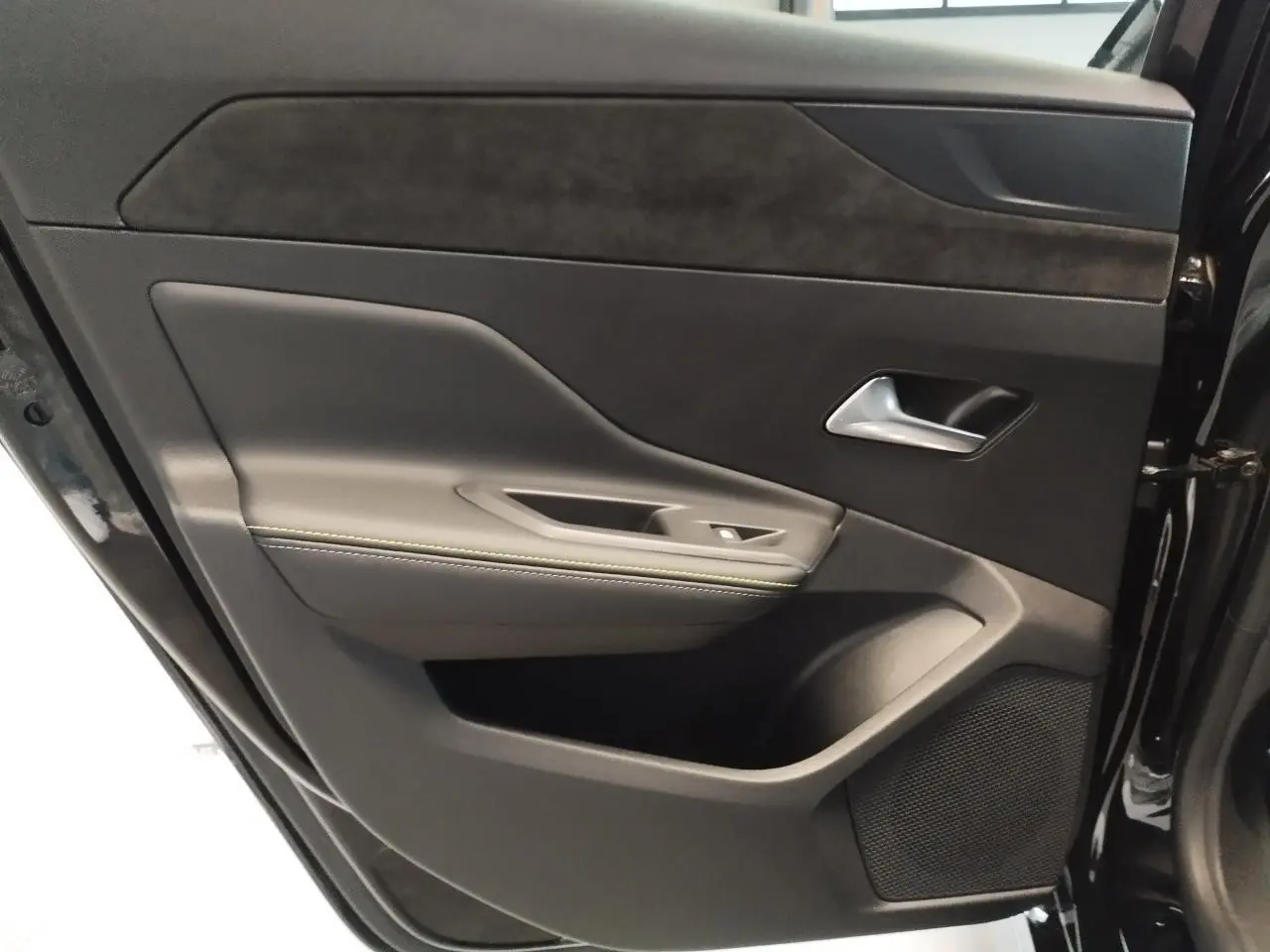 Gros plan sur la porte arrière droite noire avec surpiqûres vert Adamite et insert tissu Alcantara.