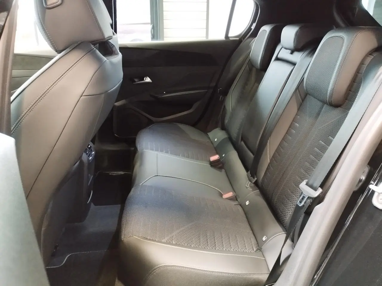 Vue intérieure côté droit des sièges arrière noirs en tissu et similicuir du Peugeot 308 hybride 2026.