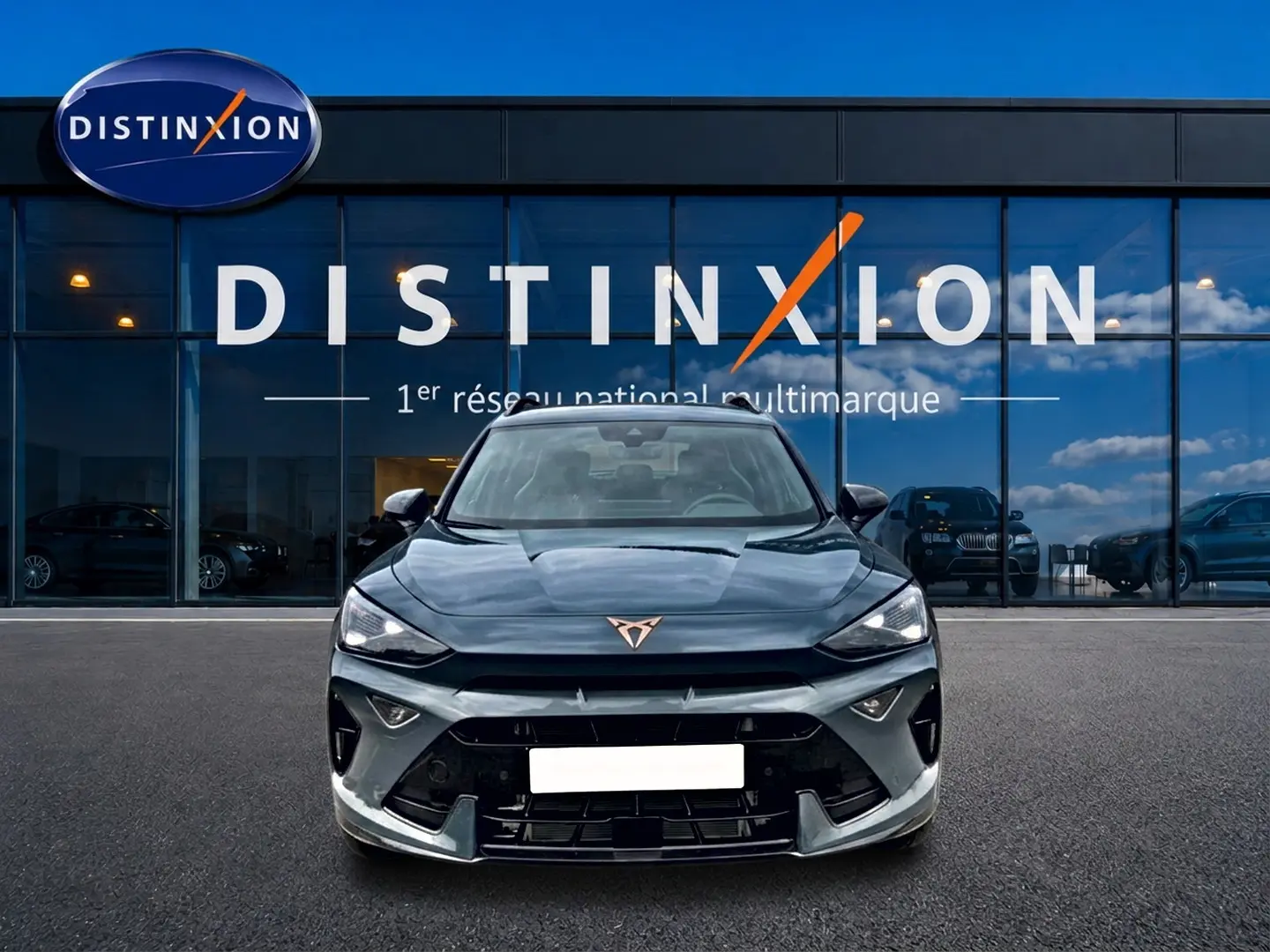 Vue frontale d'un CUPRA Formentor bleu fjord 2026 avec logo cuivré et calandre sportive devant un showroom Distinxion.