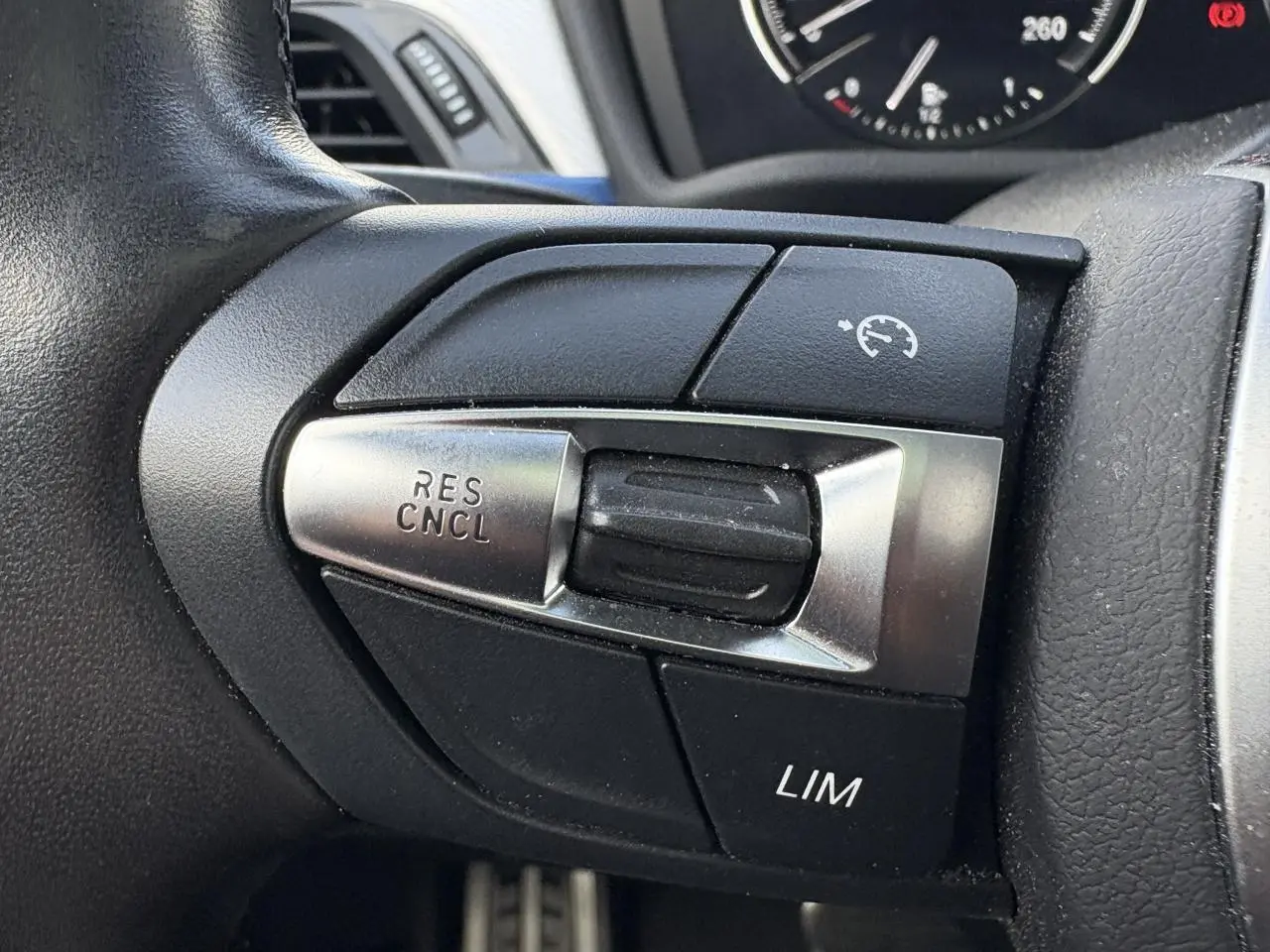 Gros plan sur les commandes de régulateur de vitesse au volant d'une BMW X2 blanche Alpine, finition M Sport.