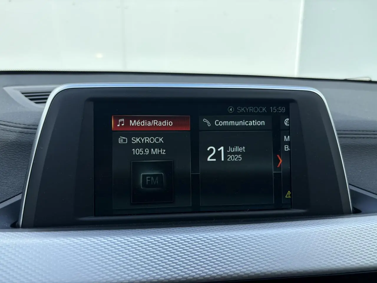 Écran multimédia central du BMW X2 blanc alpin, affichant la radio Skyrock et la date du 21 juillet 2025.