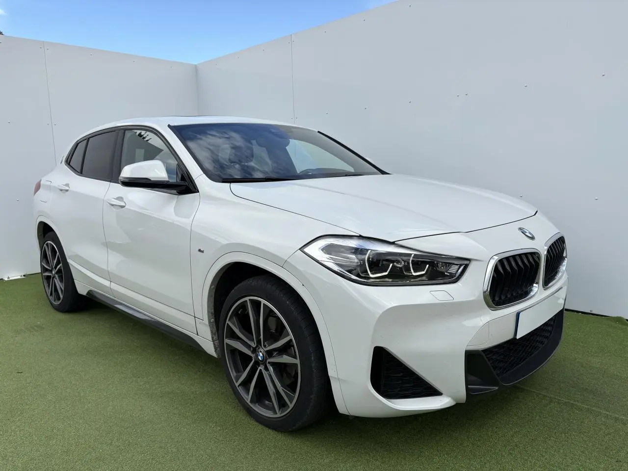 BMW X2 blanc alpin en 3/4 avant droit avec jantes M 19 pouces et toit ouvrant panoramique visible