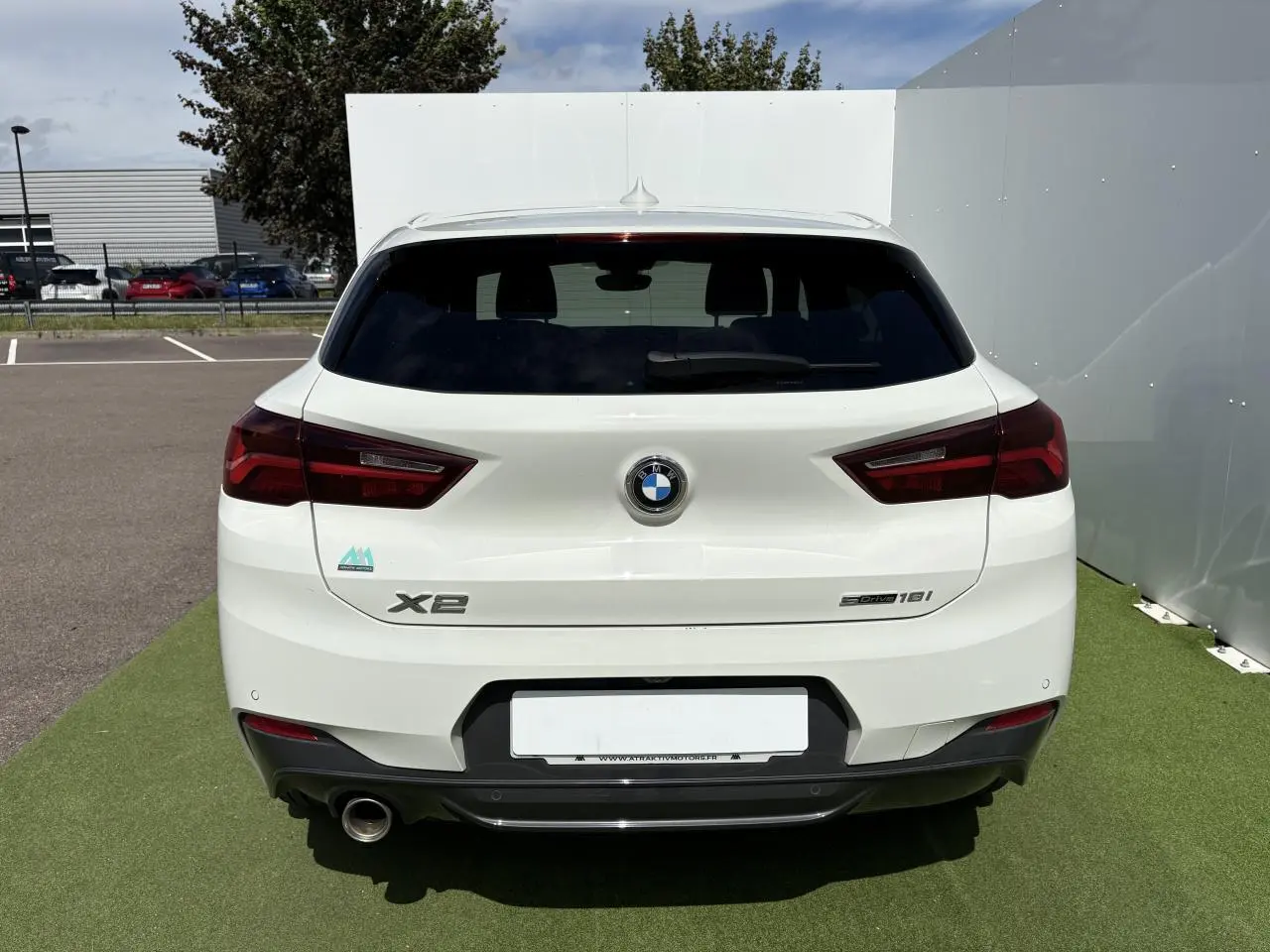 Vue arrière d'une BMW X2 blanche Alpine avec feux LED et sortie d'échappement chromée à gauche.