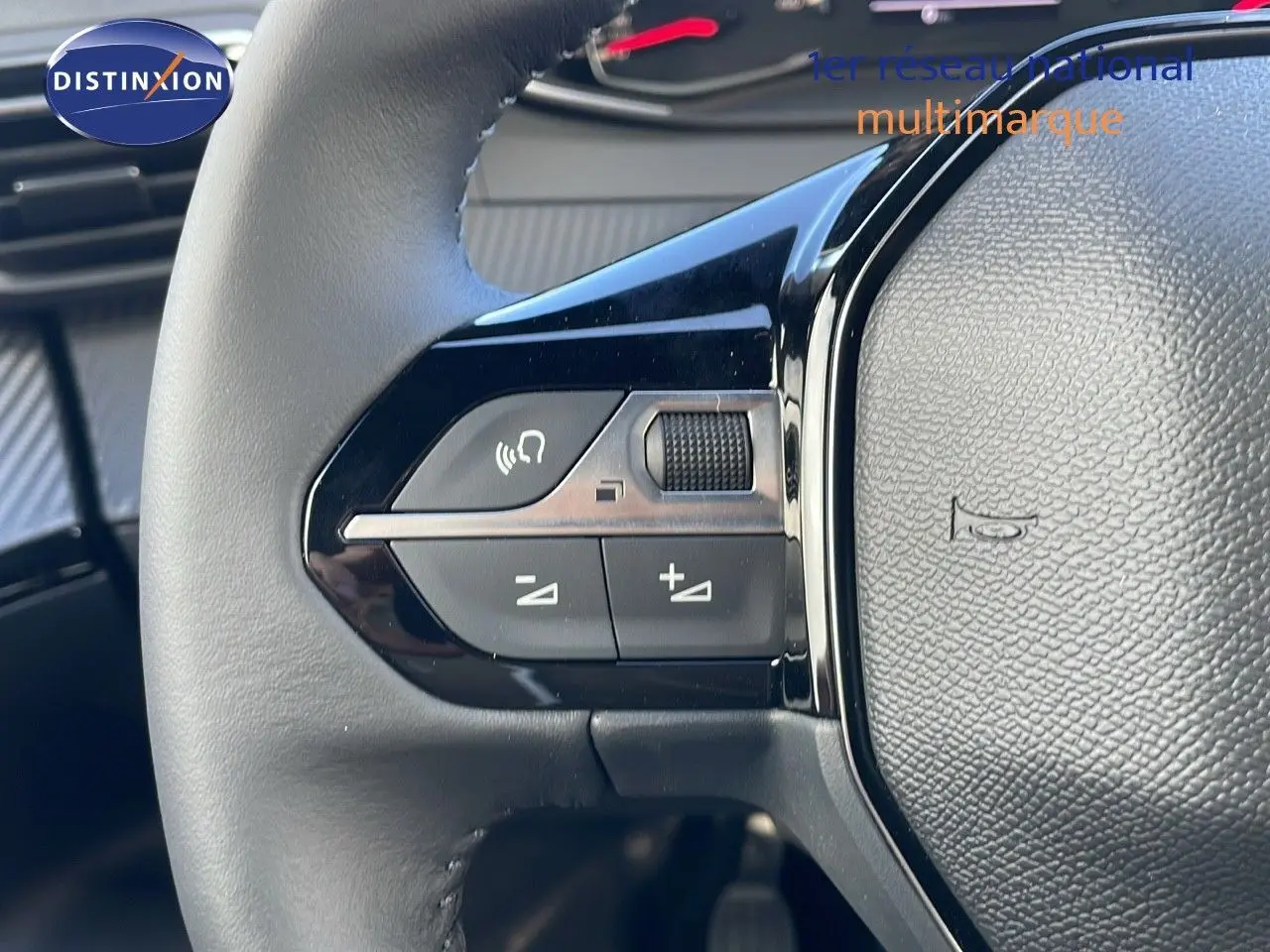 Gros plan sur les commandes du volant noir du Peugeot 2008 blanc Okenite Metal 2025 côté gauche.