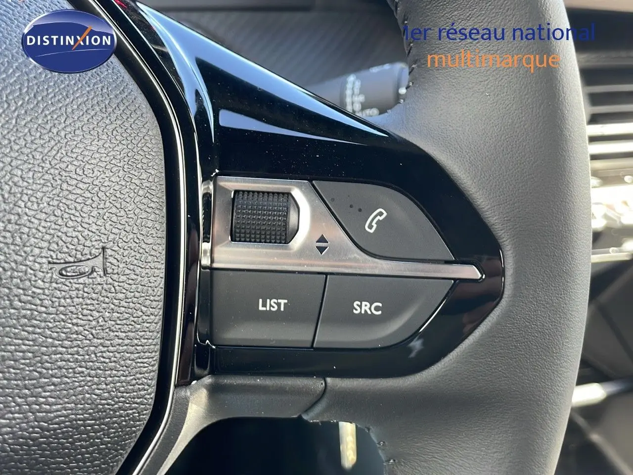 Gros plan sur les commandes gauche du volant en cuir noir du Peugeot 2008 blanc Okenite Metal, modèle 2025.