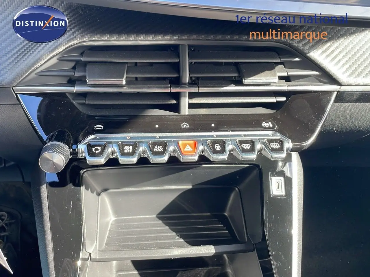 Vue rapprochée de la console centrale noire du Peugeot 2008 blanc, avec boutons de commande et aérateurs visibles.