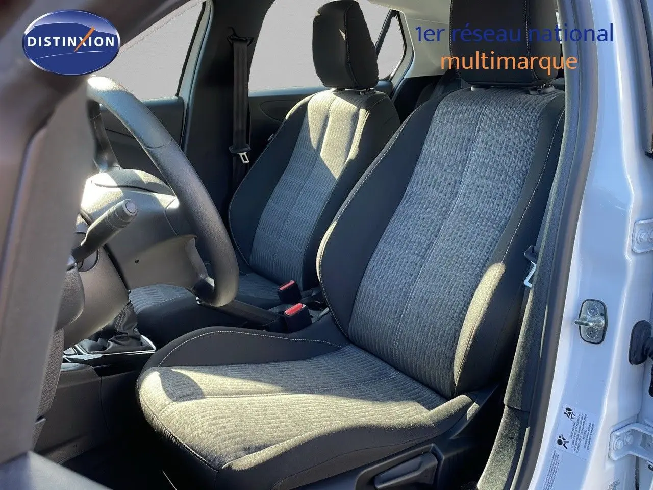 Vue intérieure côté conducteur de l'Opel Corsa blanc glacier 2022, sièges tissu gris et noir avec volant visible.