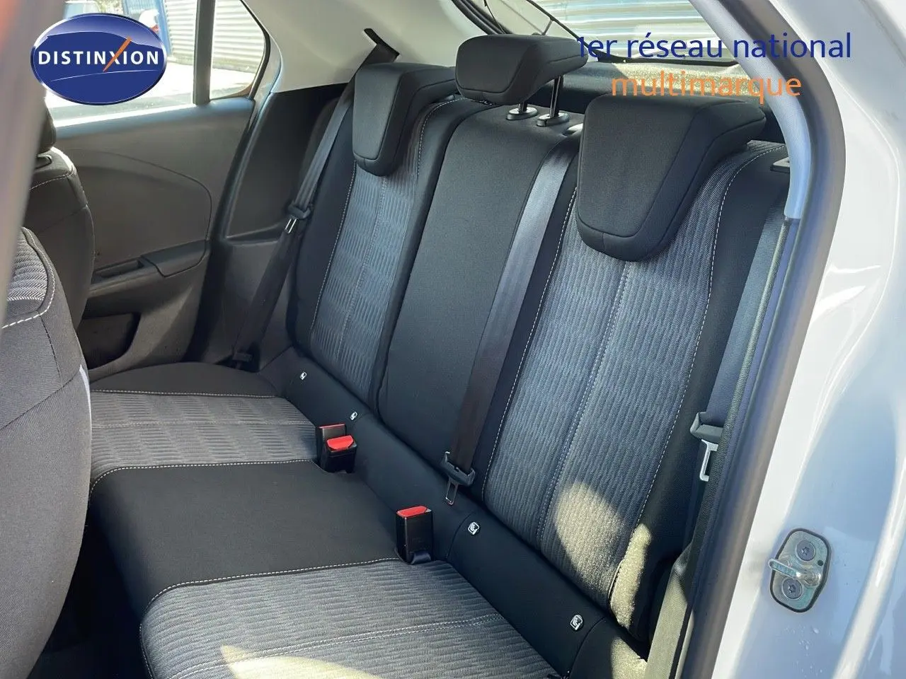 Vue intérieure sur les sièges arrière en tissu gris et noir de l'Opel Corsa blanc glacier avec porte arrière ouverte.