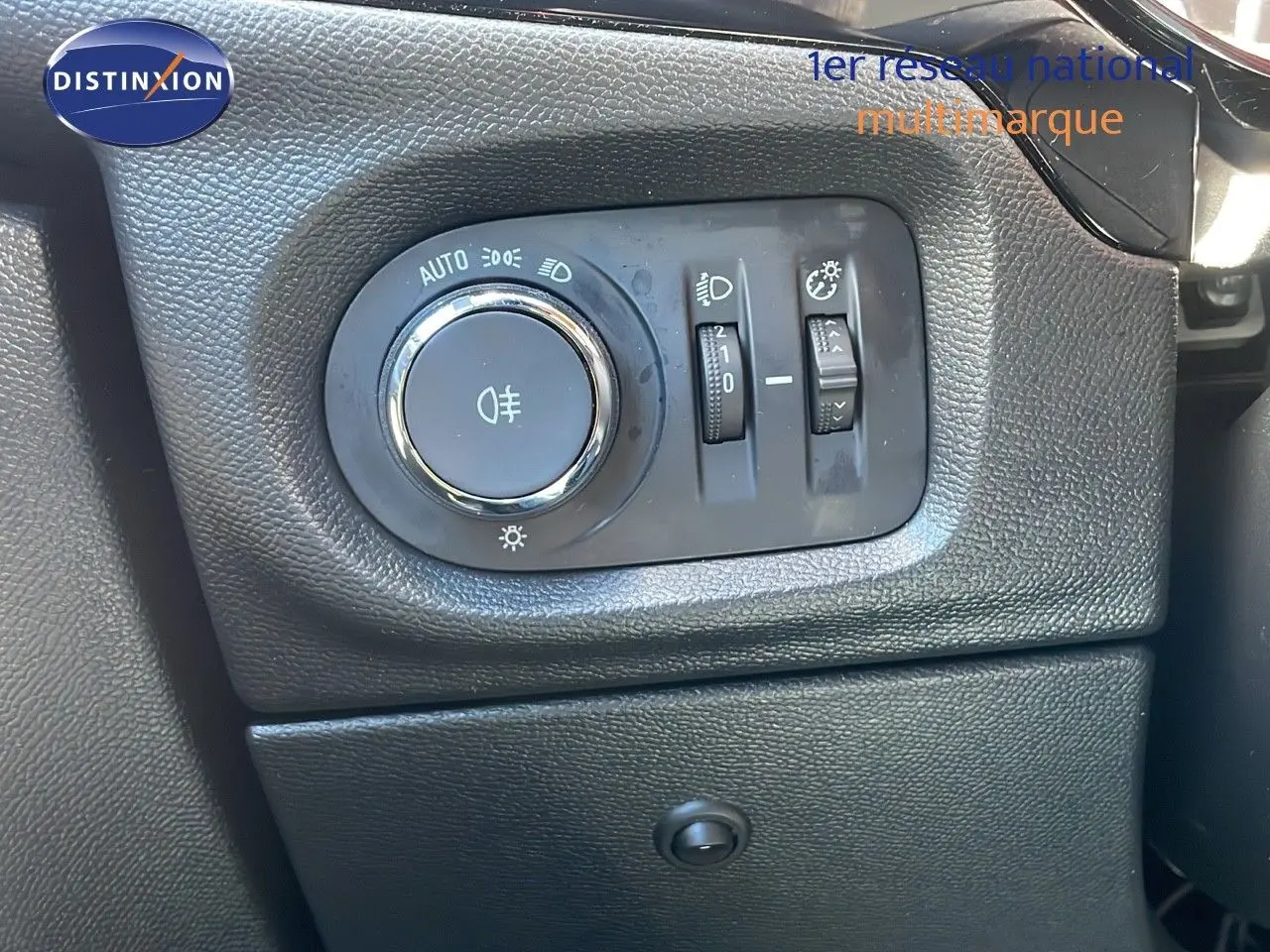 Gros plan sur la commande d'éclairage noire à gauche du tableau de bord d'une Opel Corsa blanc glacier 2022.