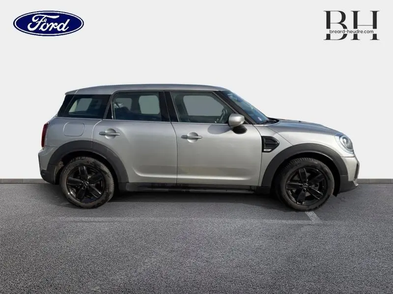 Vue de profil droit d'une MINI COUNTRYMAN Cooper 136ch Essential 2023 en Melting Silver III avec jantes noires et toit noir.