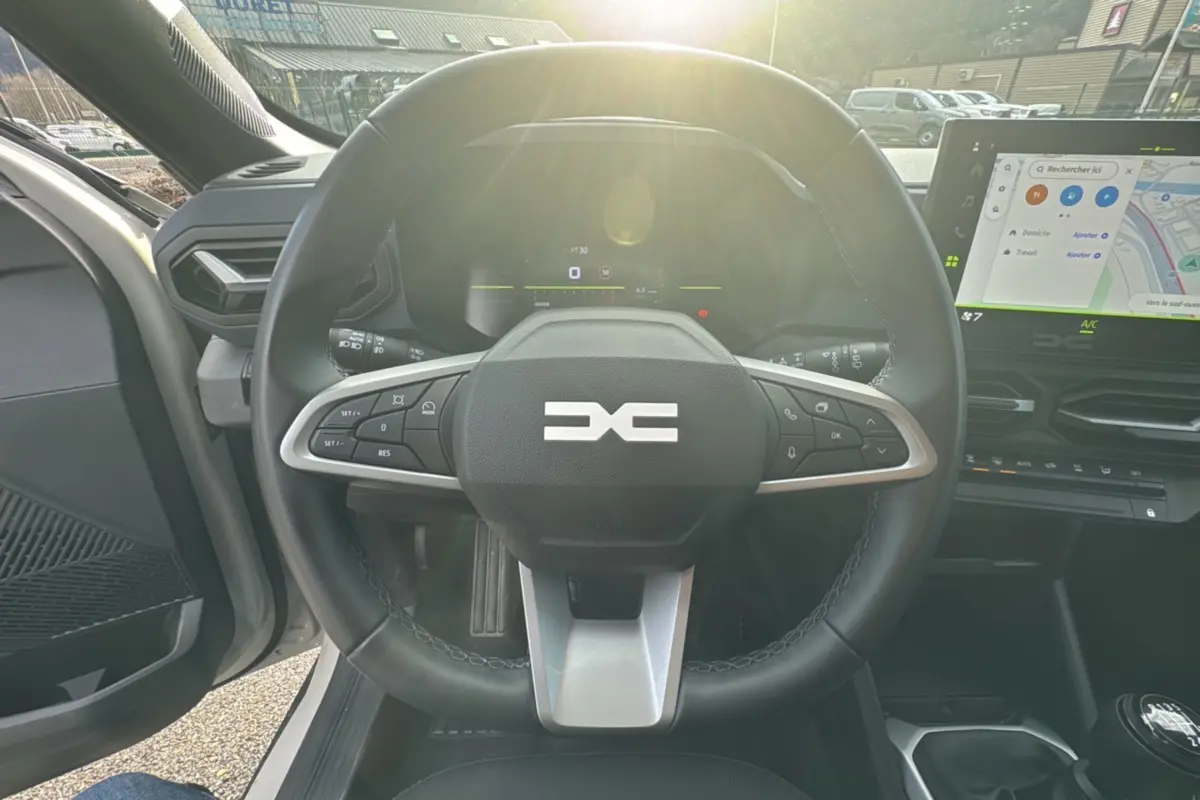 Vue intérieure centrée sur le volant cuir du Dacia Duster TCE 130 4x2 Journey avec écran tactile et levier de vitesses.