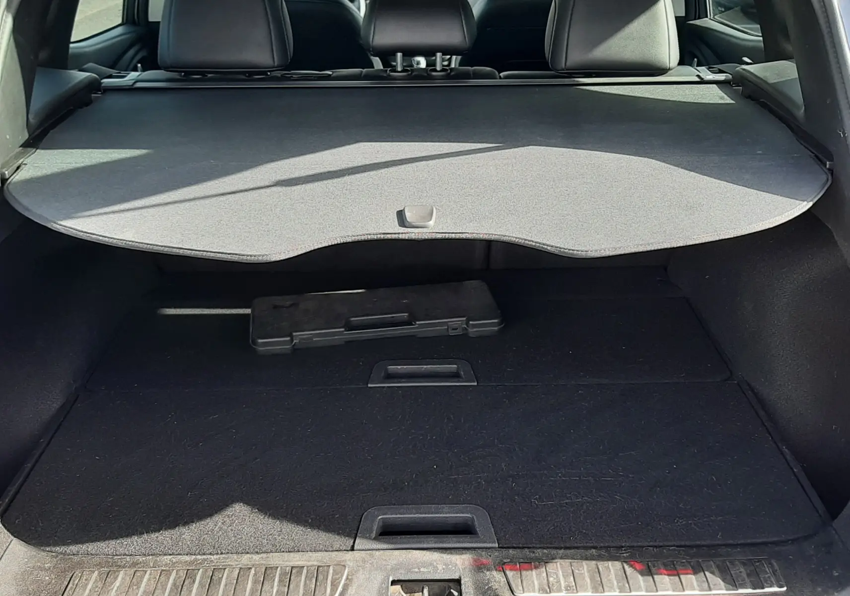 Coffre ouvert du Renault Kadjar gris titanium, vue arrière montrant la plage arrière et l’espace de chargement vide.