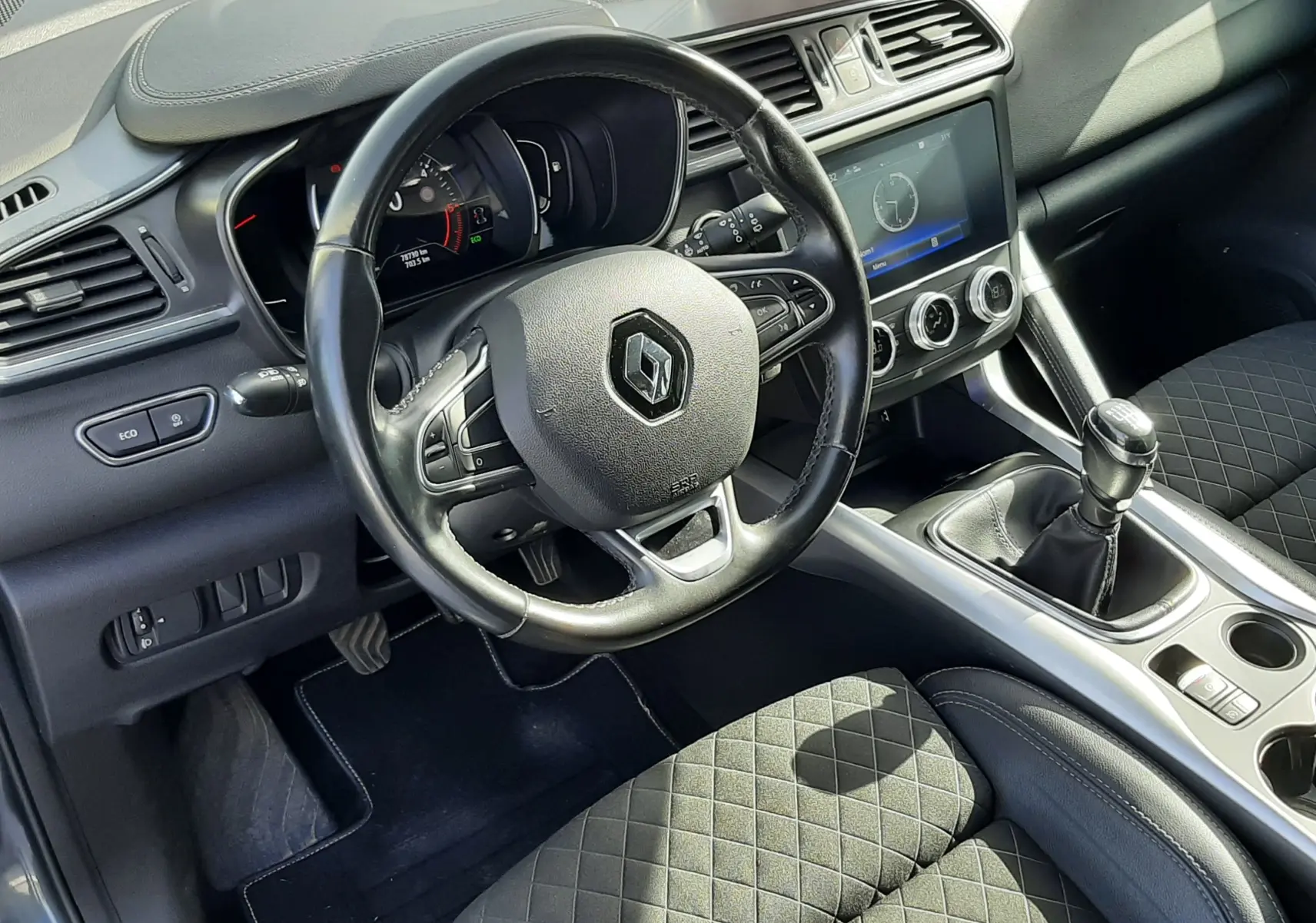 Vue intérieure côté conducteur du Renault Kadjar 1.5 Blue DCI 115ch Intens 2021, volant cuir, levier de vitesse manuel et sièges tissu noir matelassé.