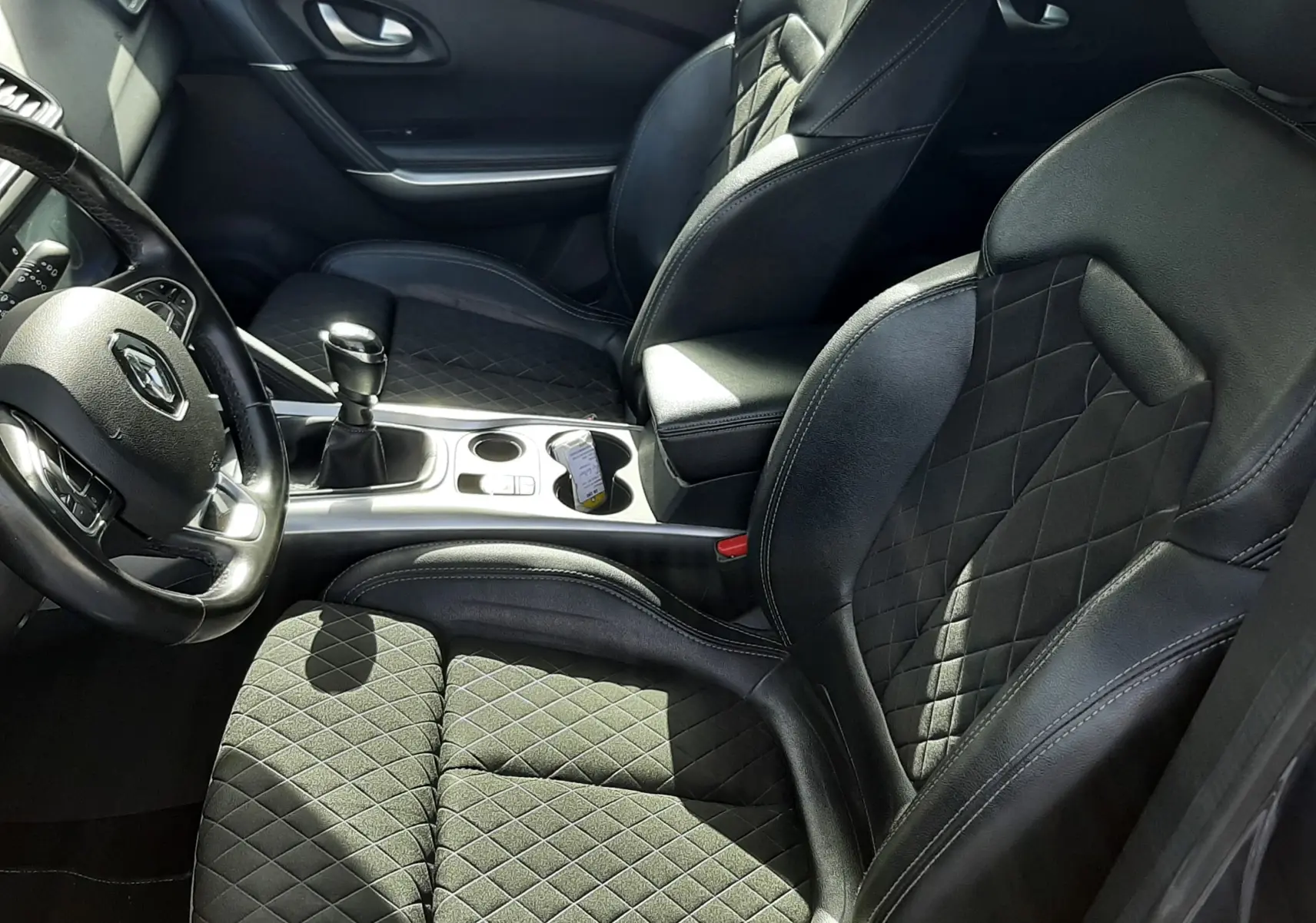 Vue intérieure côté conducteur du Renault Kadjar 2021, sièges noirs en cuir et tissu avec surpiqûres losanges.