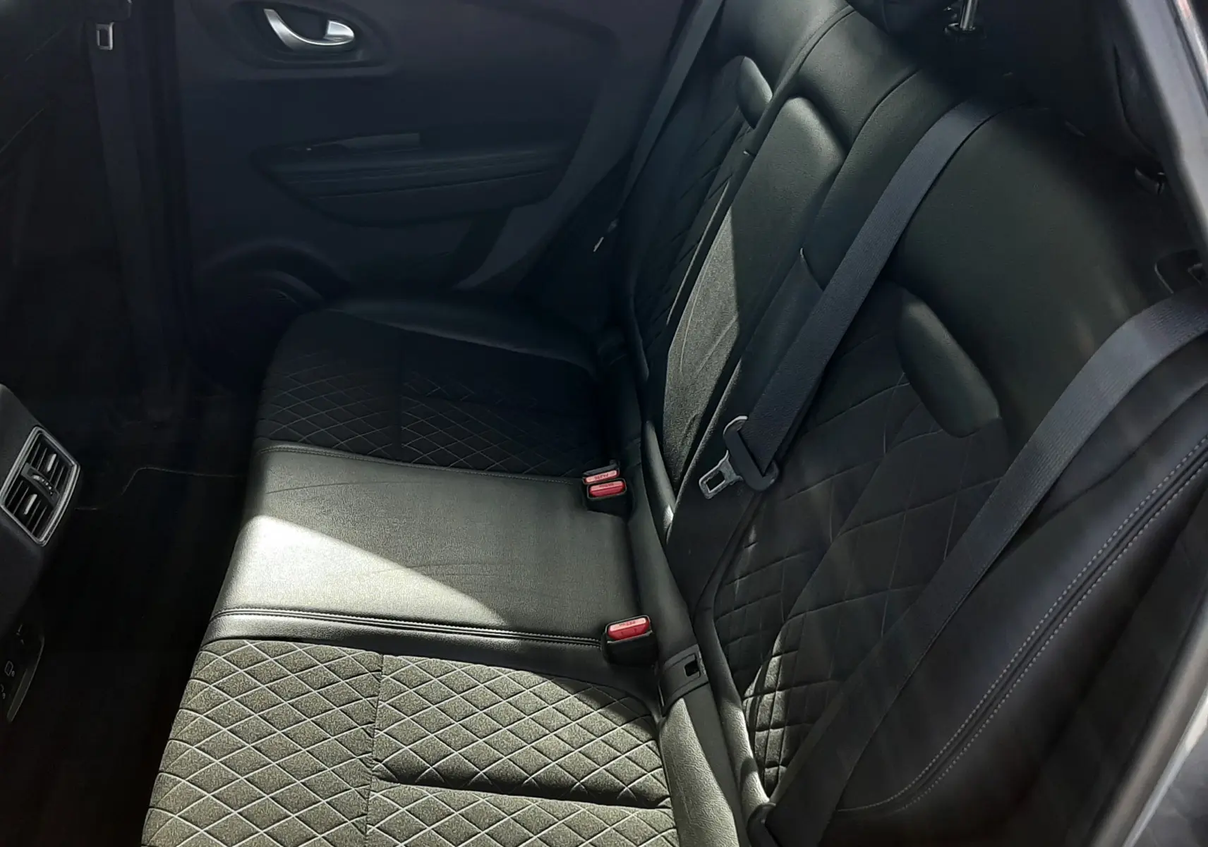 Vue intérieure côté droit des sièges arrière noirs en cuir et tissu matelassé du Renault Kadjar gris titanium.