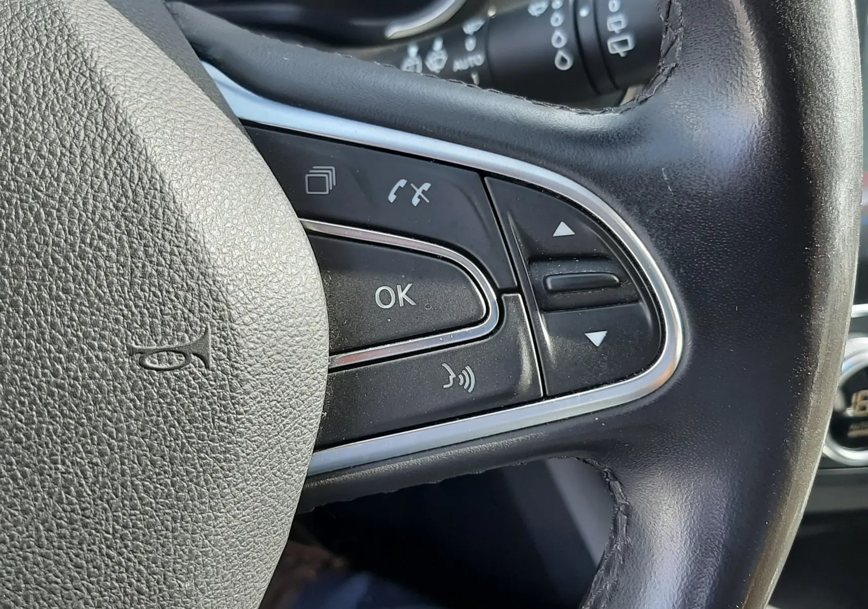 Gros plan sur les commandes multifonctions à droite du volant en cuir noir du Renault Kadjar gris titanium 2021.