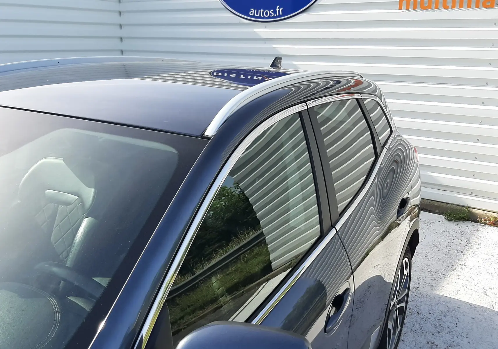 Vue 3/4 avant droit du Renault Kadjar gris titanium, mettant en valeur les vitres teintées et les barres de toit chromées.