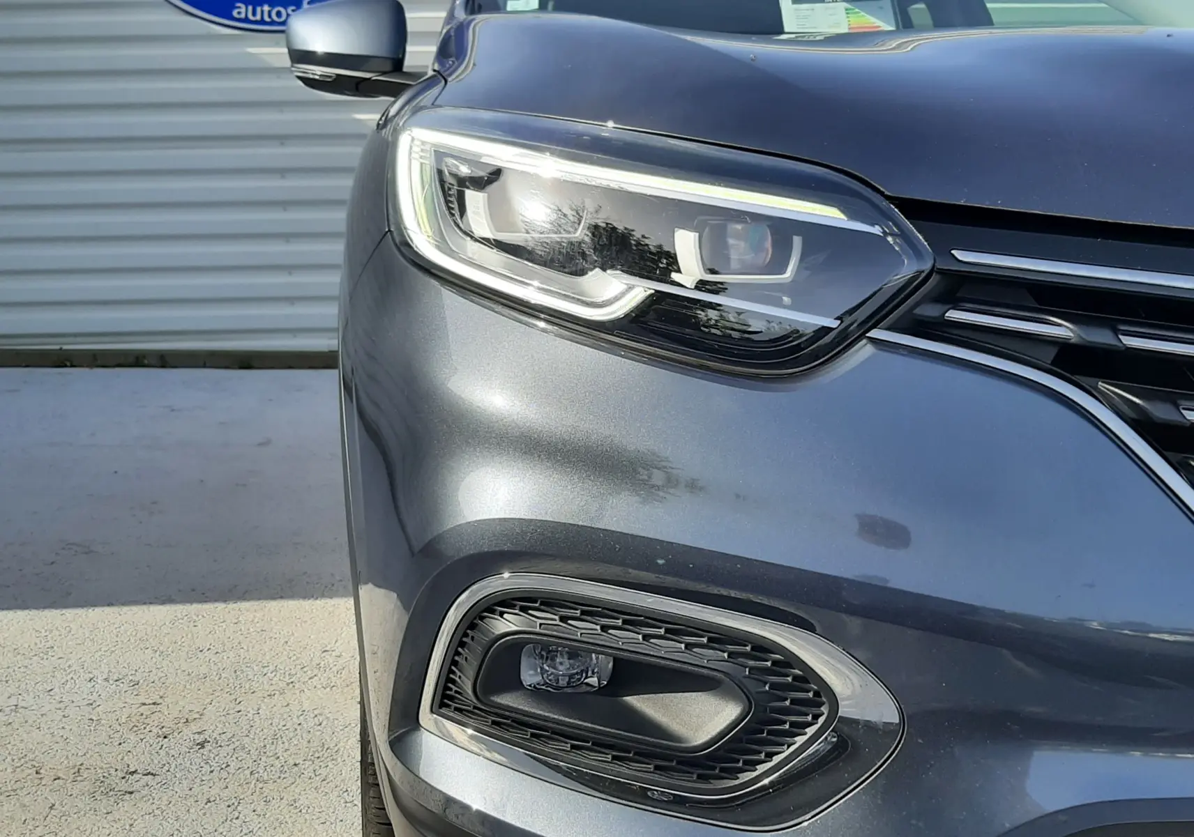 Gros plan sur l'avant gauche du Renault Kadjar gris titanium 2021, mettant en valeur le phare LED et la calandre.