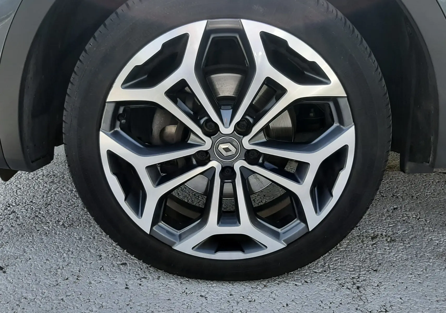 Gros plan sur la jante alliage bi-ton avec logo Renault, sur roue avant droite du Kadjar gris titanium.