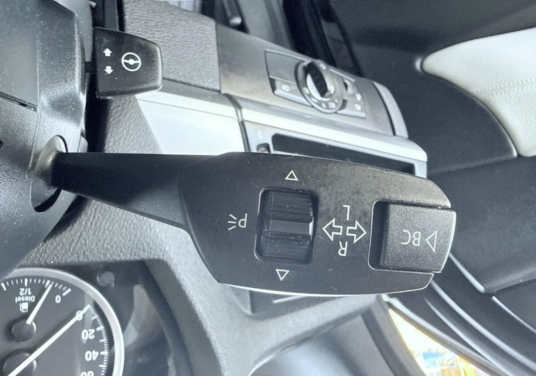 Gros plan sur la commande de clignotant et régulateur de vitesse dans l’habitacle noir d’une BMW X6 noire, vue côté gauche.