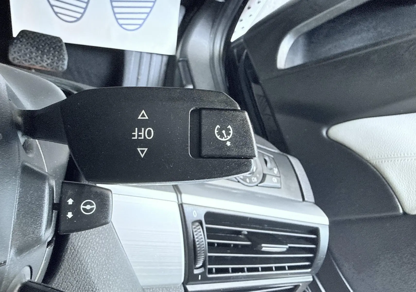 Gros plan sur la commande de régulateur de vitesse dans l’habitacle noir et gris d’une BMW X6 noire, côté gauche du volant.